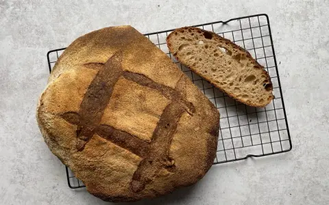 Chleb pszenno orkiszowy, świeżo upieczony, z chrupiącą skórką i puszystym wnętrzem, czeka na kromkę.