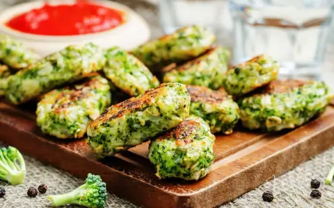 Deliciosas bolitas de brócoli, perfectas para tus recetas con brócoli. Servidas con salsa roja y un toque de pimienta.
