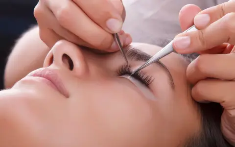 Pose de cils pour un rehaussement cil et teinture. Une esthéticienne applique des extensions avec précision.