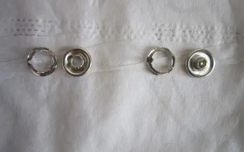 Quatre pièces de bouton pression métal argenté, prêtes à poser sans pince.
