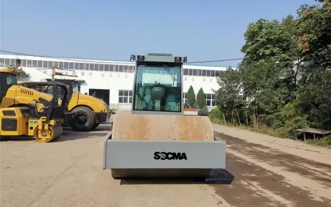 Nowy walec maszyna SOCMA gotowy do pracy na budowie. Obok stoją inne żółte maszyny budowlane.
