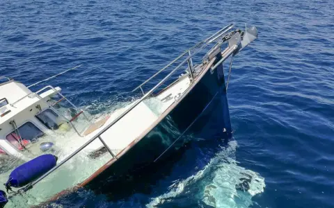 Ein **bilge boot** sinkt im tiefblauen Meer. Rettungsringe und Fender treiben im Wasser.