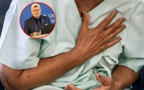 Lekarz omawia objawy grypy wariant K. Pacjent trzyma się za klatkę piersiową, odczuwając dyskomfort.