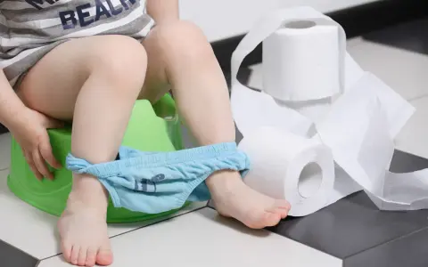 Dziecko na nocniku, obok rolki papieru toaletowego. Wygląda na to, że ma wodnistą biegunkę.