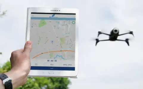 Tablet zeigt eine Karte und Drohnen-Apps. Eine Drohne fliegt im Hintergrund.