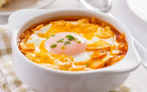 Sopa castellana en cuenco blanco con huevo escalfado y picatostes.