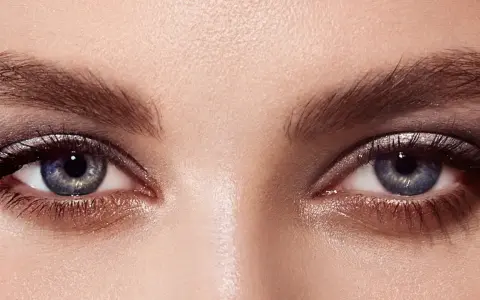 Ojos con un cautivador maquillaje con sombras azules y plateadas, realzados por pestañas largas y definidas.