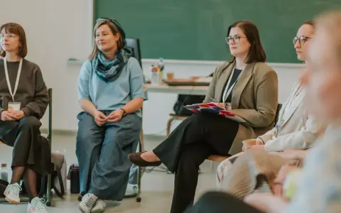 Grupa osób siedzi w kręgu, dyskutując o tym, ile nauczyciel ma urlopu.