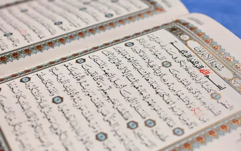 Ein aufgeschlagenes Korankonvolut mit arabischer Schrift und dekorativen Rändern. Es erinnert an die Lehren des Islams und die Geschichten von Jinn.
