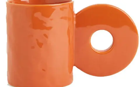 En orange mugg med ett cirkulärt handtag. Perfekt för ditt keramik hemma utan ugn-projekt.