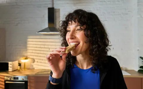 Frau isst einen Riegel, die perfekte Energie für das, was essen vor dem Training.