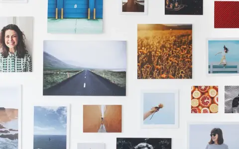 Un collage di fotografie su una parete bianca: paesaggi, ritratti, natura. Un'idea su come esporre fotografie in modo creativo.