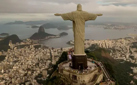 Majestatyczny pomnik Rio de Janeiro Jezus wita turystów, rozpościerając ramiona nad tętniącym życiem miastem i zatoką.