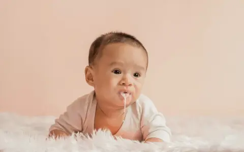 Söt bebis med mjölk runt munnen, ser ut som att bebis spyr mycket.