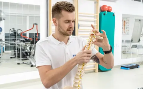 Fizjoterapeuta z wyższej szkoły rehabilitacji w Warszawie pokazuje model kręgosłupa.