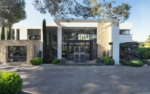 Une villa moderne avec des pierres apparentes et de grandes baies vitrées, parfaite pour construire une maison bioclimatique.