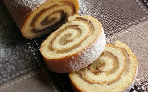 Pyszna, odwrócona rolada z jabłkami, posypana cukrem pudrem, kusi apetycznym wyglądem. Idealna na deser.