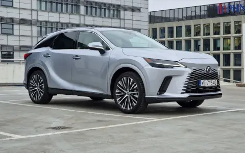 Srebrny Lexus RX 350h zaparkowany przed nowoczesnym budynkiem.