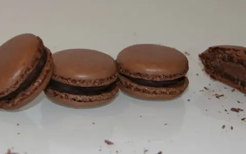 Trois macarons au chocolat et un croqué, parfaits pour une recette macaron chocolat.