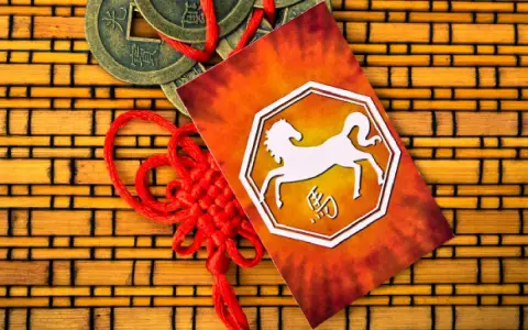 Chiński znak zodiaku 1990 - koń. Obok monety i czerwony sznurek.