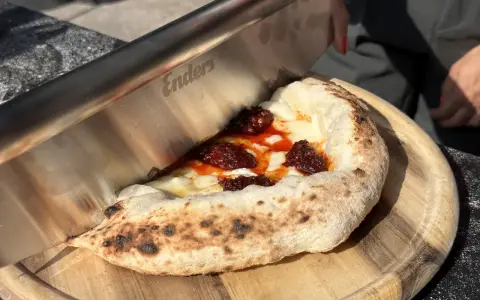 Ein Messer schneidet ein Stück Pizza mit geschmolzenem Käse und würziger Tomatensauce. Der luftige pizzateig napoli ist perfekt gebacken.