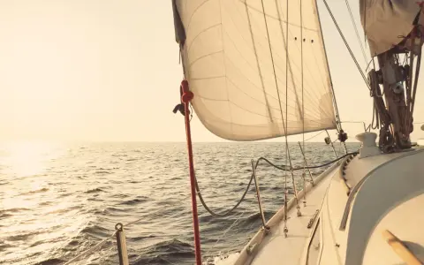 Segelboot gleitet über ruhige See im Sonnenuntergang. Die Segel sind straff gespannt, bereit für die nächste Etappe. Ein Moment der Ruhe vor dem **ausbessern der Segel** für die nächste Reise.