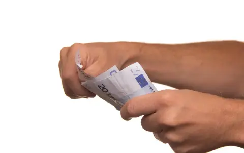 Dłonie trzymają banknoty euro. To może być symboliczne zawiadomienie o uchyleniu zajęcia, gdy pieniądze wracają do właściciela.