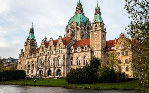 Imponujący Nowy Ratusz w Hanowerze, jedna z głównych atrakcji miasta, z zieloną kopułą i wieżami, nad jeziorem.
