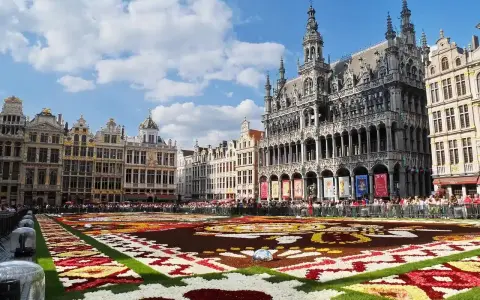 Grand Place, Brussels, with a vibrant flower carpet and ornate buildings under a blue sky.