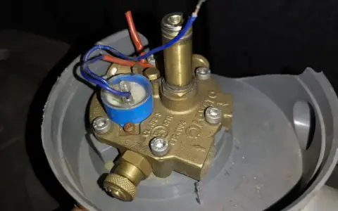 Uszkodzony elektrozawór LPG. Widoczne luźne przewody i korozja, potencjalne objawy awarii.