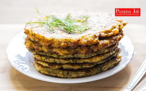 Stos placków z cukinii, idealnych jako dodatek do dania lub samodzielna przekąska. Ziołowy aromat i chrupiąca skórka zachęcają do spróbowania.