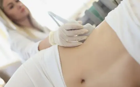 Ärztin untersucht Bauch einer Frau mit Ultraschall, um Schmerzen linke Seite Taille zu diagnostizieren.