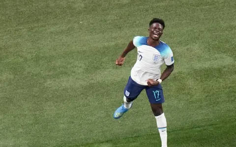 Bukayo Saka celebra un gol con euforia en el campo de fútbol.