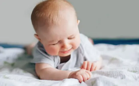 Ein süßes Baby liegt auf dem Bauch, die Augen geschlossen, als würde es die Welt entdecken. Ein Zeichen des baby 6 wochen wachstumsschub.