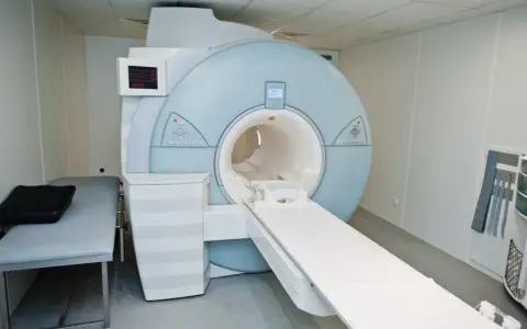 Nowoczesny aparat rezonansu magnetycznego (MRI) w gabinecie lekarskim z kozetką.