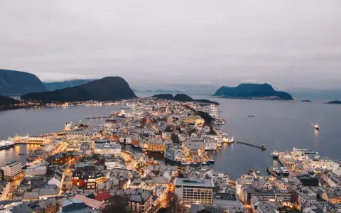 Vacker stad vid vattnet i Norge, med upplysta hus och berg i bakgrunden. En dröm att bila i Norge.