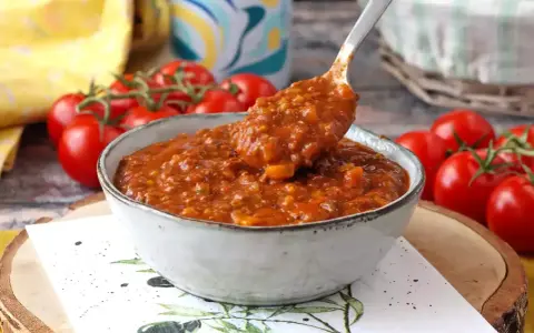En skål med mustig bolognese, perfekt för ett gott bolognese recept. Färska tomater i bakgrunden.