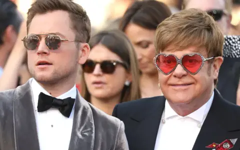 Taron Egerton och Elton John, som spelar rollistan i Rocketman, poserar på röda mattan. Elton bär sina ikoniska hjärtformade glasögon.