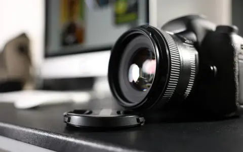 Czarne body lustrzanki cyfrowej z obiektywem i dekielkiem na czarnym blacie. Zastanawiasz się dslr co to? To właśnie to!