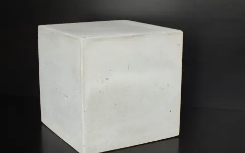 Ein Würfel aus hellem Beton C30/37 steht auf schwarzem Untergrund.