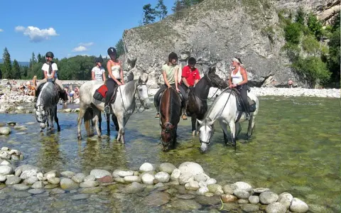 Konni jeźdźcy na koniach w rzece, relaksują się w ośrodku jeździeckim Bukowina Tatrzańska.