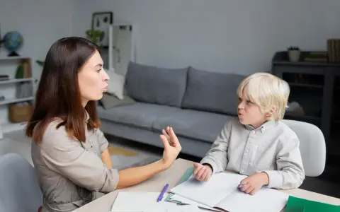 Terapeuta pracuje z dzieckiem, które ma orzeczenie o specjalnych potrzebach edukacyjnych, ćwicząc wymowę.