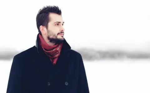 Mężczyzna w granatowym płaszczu i bordowym szaliku z wzorem. Idealne połączenie, by zadać sobie pytanie: jaki szalik do granatowego płaszcza?