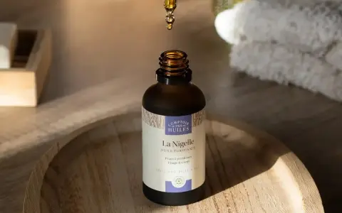 Une goutte d'huile de nigelle, aux propriétés anti inflammatoires, tombe dans un flacon. Idéal pour peaux à problèmes.