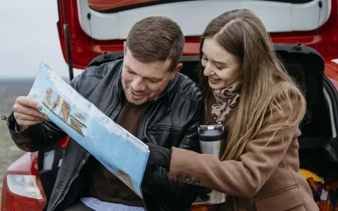 Para planować podróż i ubezpieczenie samochodu na wyjazd za granicę, para przegląda mapę.