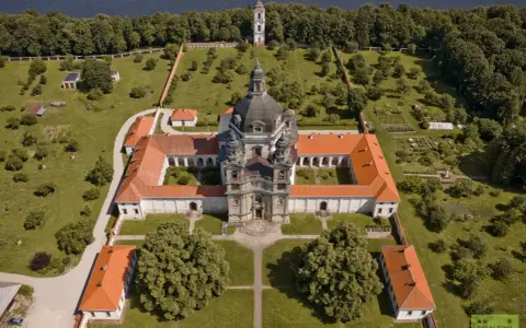 Litwa atrakcje: imponujący klasztor z kopułą i wieżą, otoczony zielenią i ogrodem, nad brzegiem jeziora.