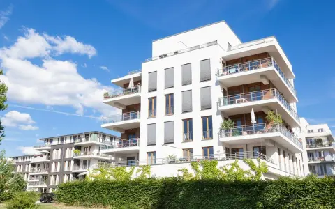 Immeubles modernes avec balcons fleuris, sous un ciel bleu. Un projet immobilier qui pourrait bénéficier de la loi Borloo pour son accessibilité.