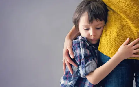 Niño de 6 años abraza a su madre con apego excesivo, buscando consuelo en su abrazo protector.