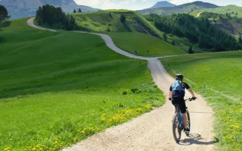 Rowerzysta przemierza malowniczą dolnośląską krainę rowerową, wijącą się wśród zielonych wzgórz i kwiecistych łąk.