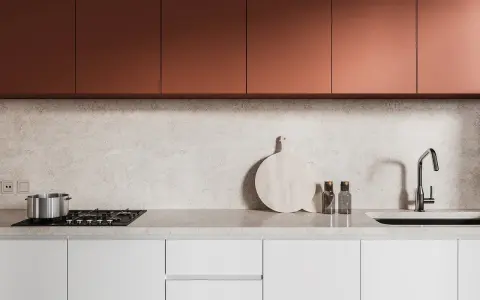 Crédence de cuisine moderne avec placards cuivrés, plan de travail en marbre clair, plaque de cuisson, évier et ustensiles.